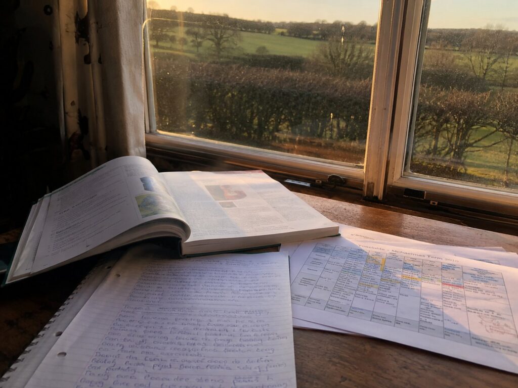 Tutoring notes, biology textbook, and a Michaelmas 2010 timetable on a wooden desk — where Rich Thompson's tutoring career began